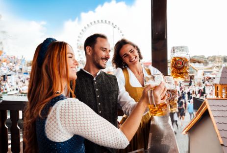 Gäste trinken PAULANER Oktoberfestbier auf dem Balkon des Festzeltes.